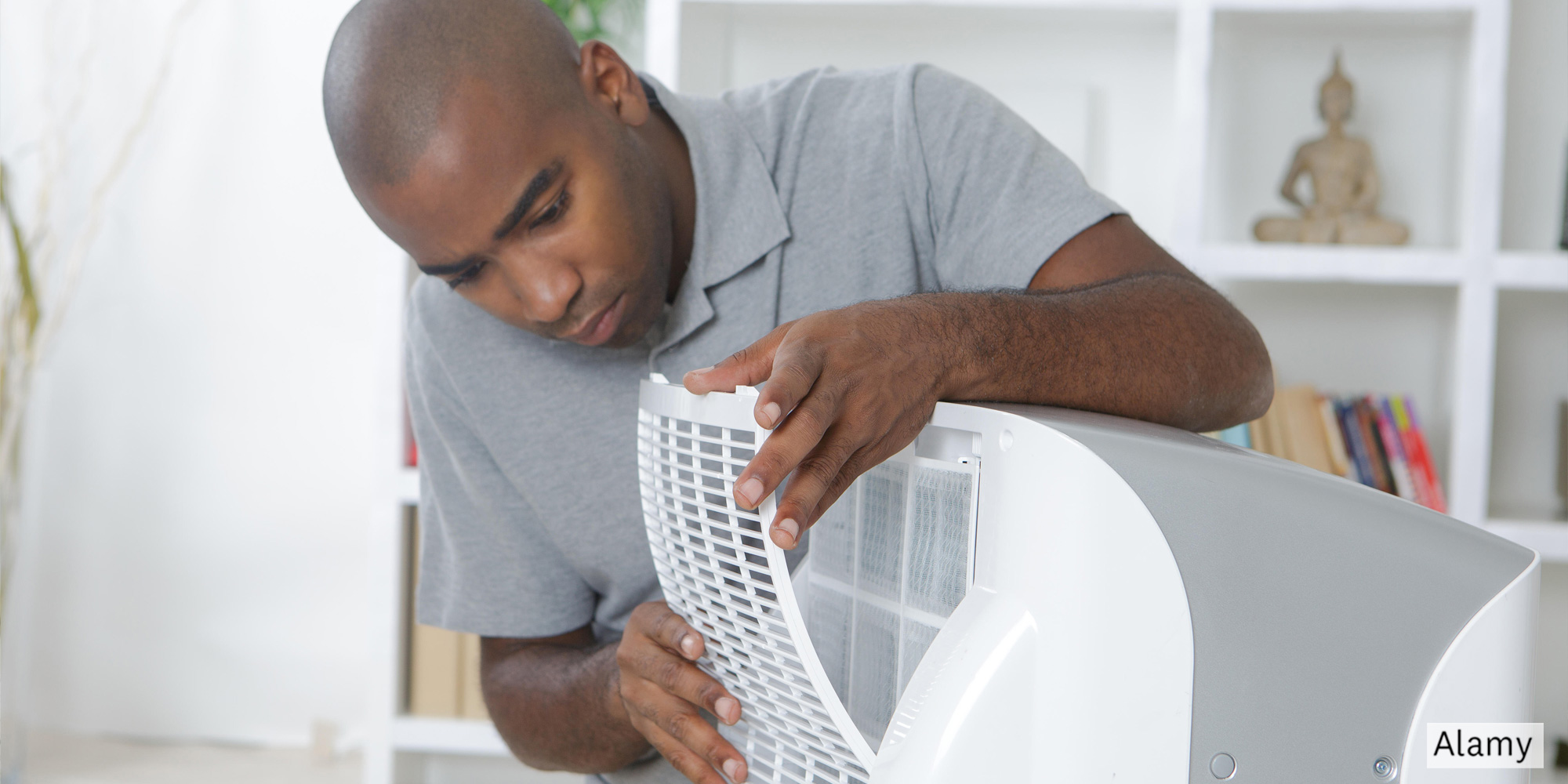 Man installing front grate on air conditioner
