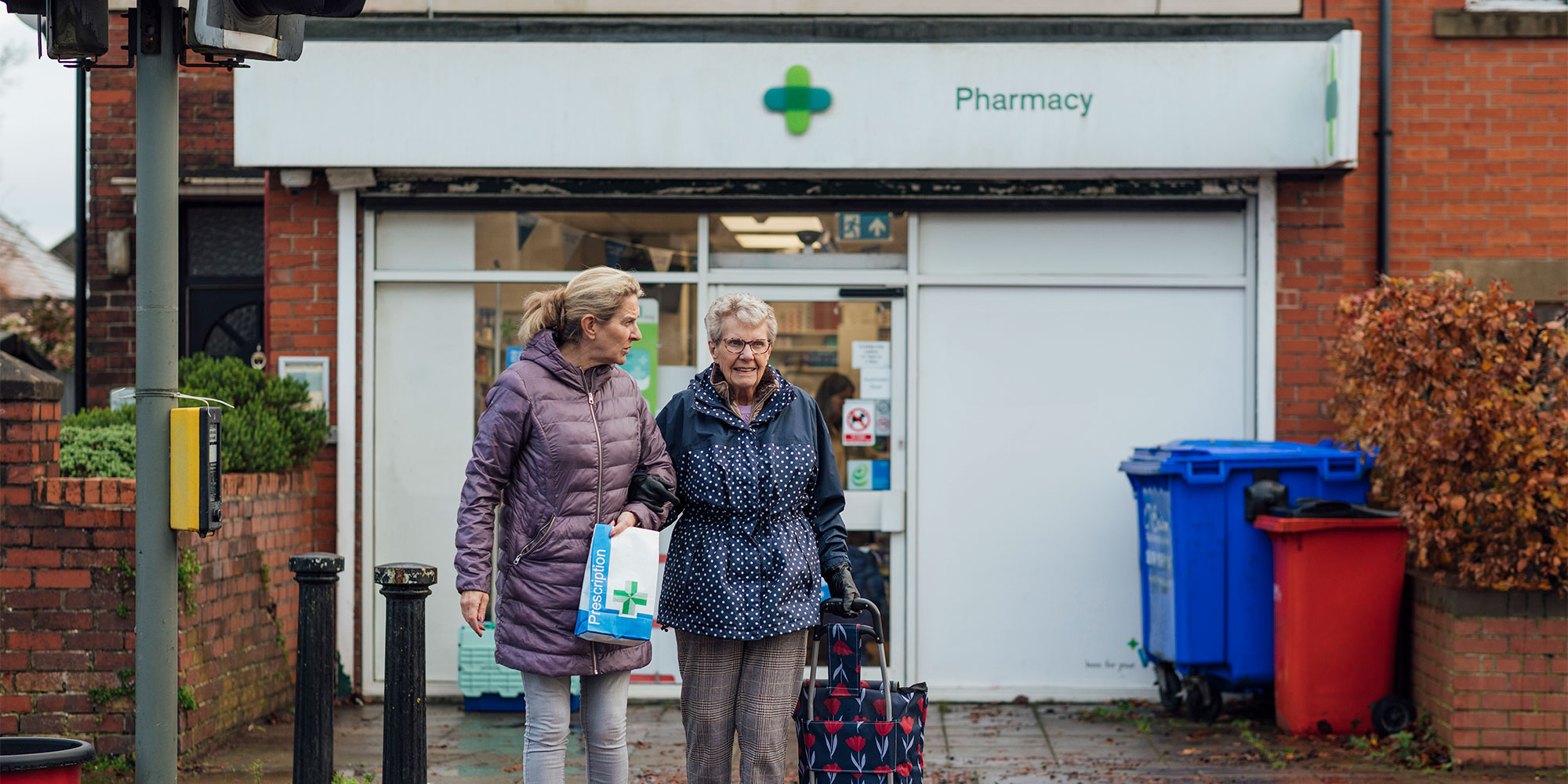 Two women walking out of a pharmacy holding a prescription