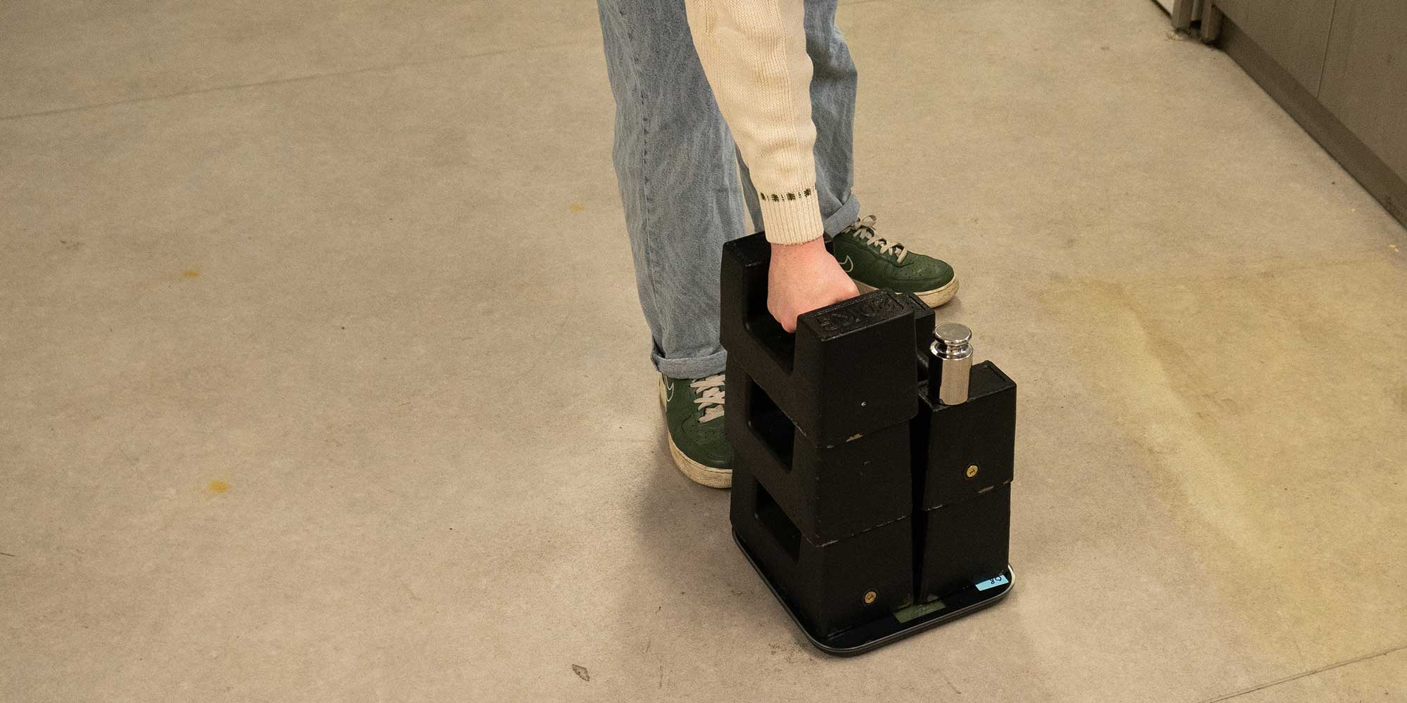 A scale with 5 20kg weights on top of it, as well as a 1kg weight